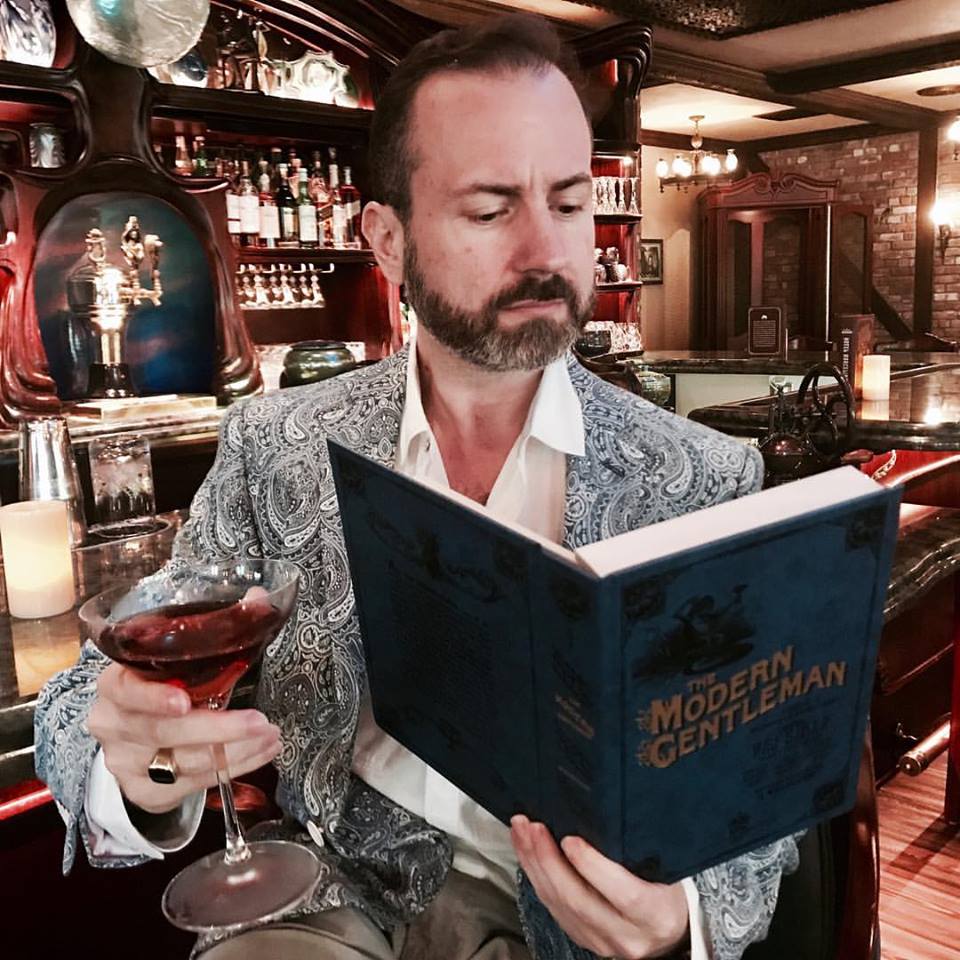 Picture of John Champion reading the Modern Gentleman while having a cocktail.