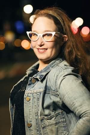 Image of Sharon Simon wearing a denim jacket and white cat-eye glasses