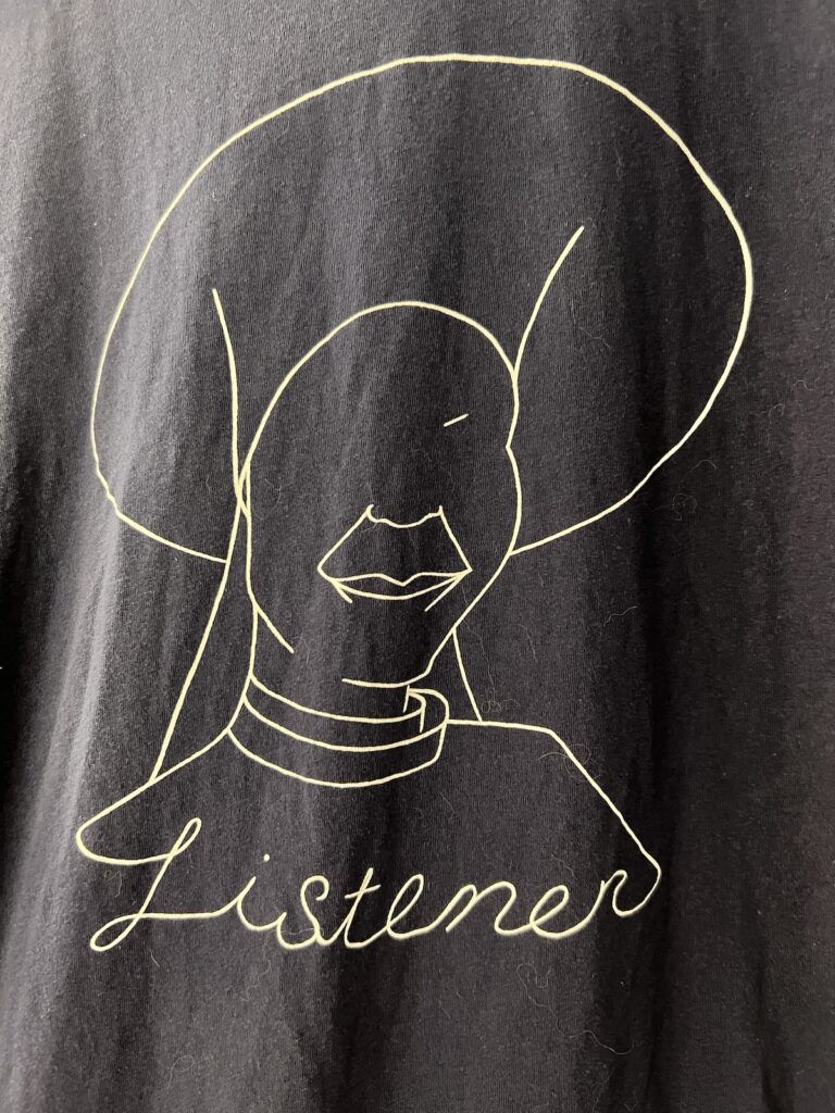 A line drawing on a tee shirt of Guinan from Star Trek The Next Generation and at the bottom the line drawing has the word "listener"